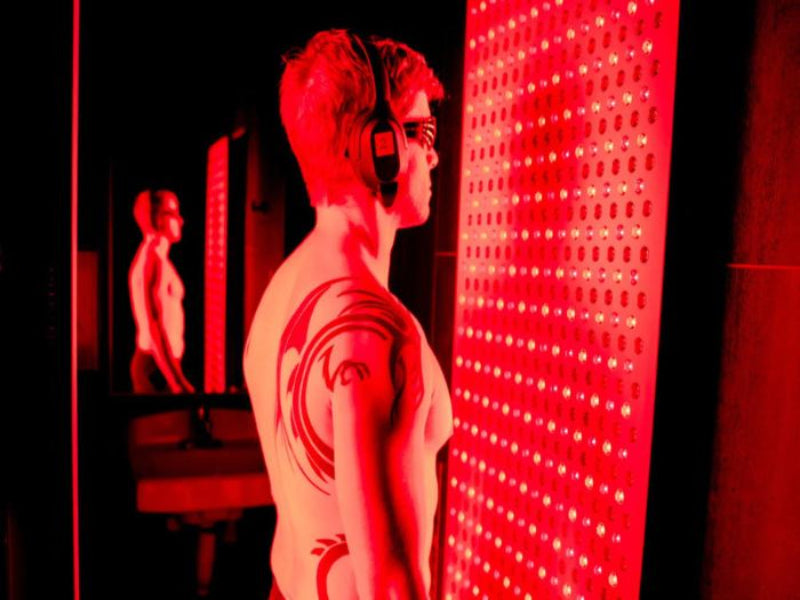 man wearing headphones standing in front of commercial red light panel