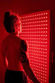 man standing in front of red light therapy panel 