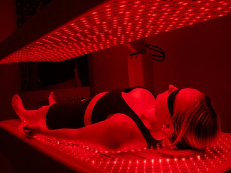 woman laying in mito red light recharge bed while it is turned on 